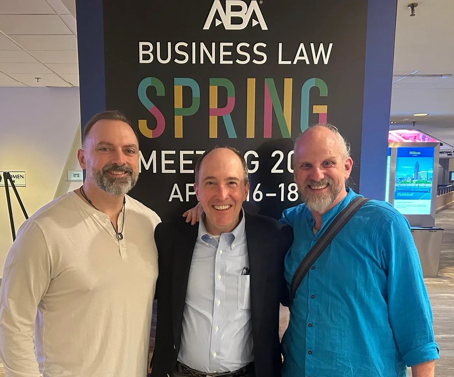 Keith Dugas, Tim Reiniger and Paul Knowles standing together in front of an ABA Business Law Spring Meeting 2026 banner at the Atlanta Hilton.